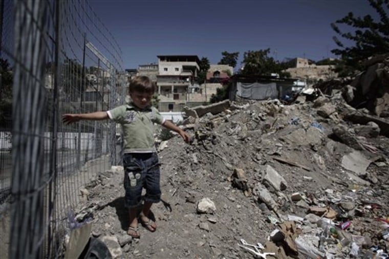 A Palestinian child walks near rubble in the east Jerusalem neighborhood of Silwan on Monday. Jerusalem's mayor, Nir Barkat, pressed ahead  with a contentious plan to raze 22 Palestinian homes, that were illegally built, to make room for a tourist center. 